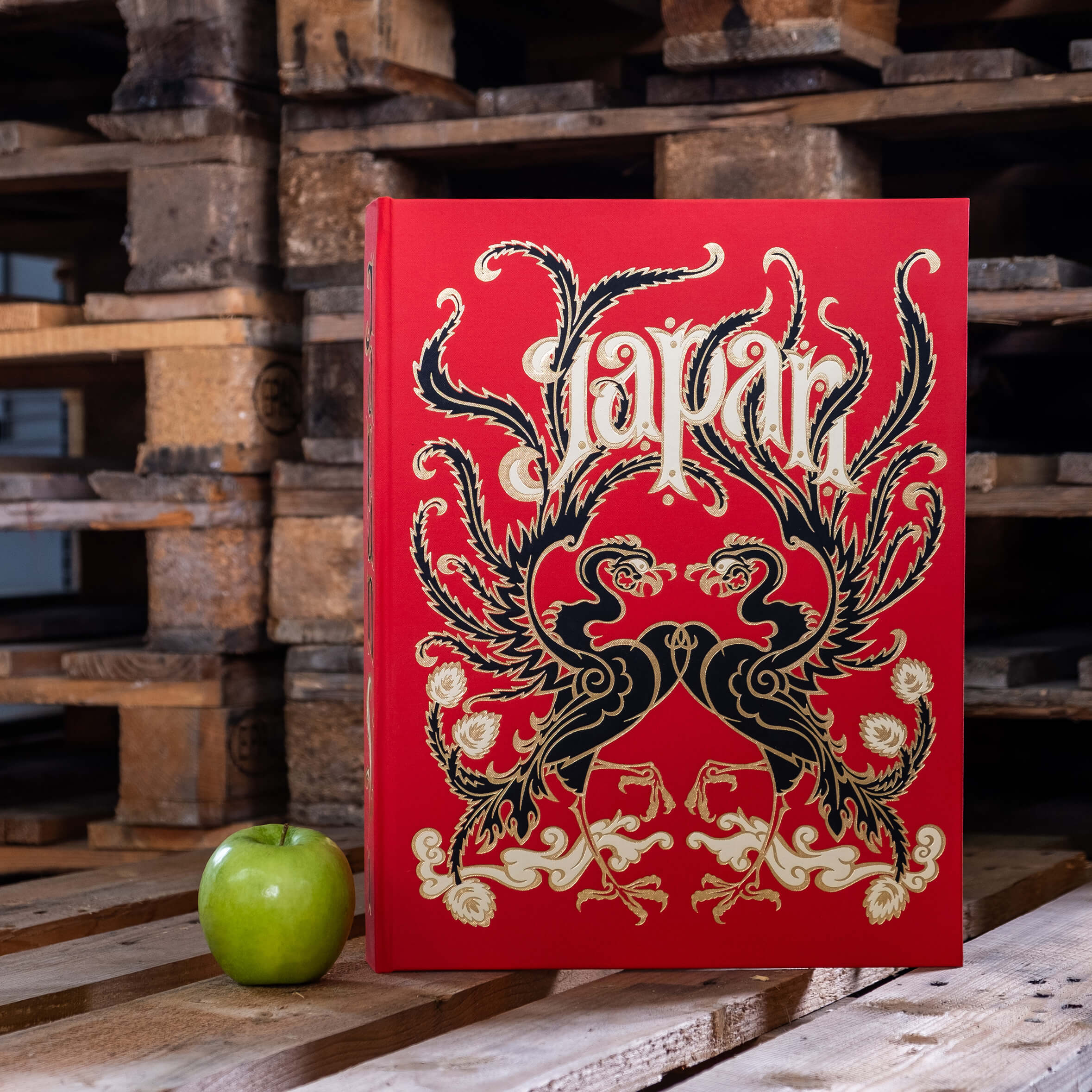 Beispielbuch Japan Stil in rot mit Schriftzug Japan mit grünem Apfel daneben auf Paletten stehend